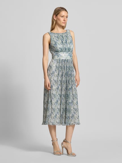 Frauenmodel trägt Cocktailkleid mit U-Boot-Ausschnitt von Swing, taillierte Passform, Midikleid, floral gemustert, Ganzkörperansicht von vorne.