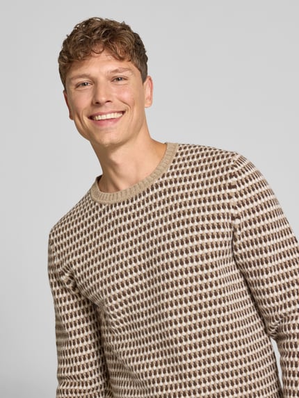 Männermodel trägt Pullover aus Wolle mit Strukturstrick von GANT, mehrfarbig, Rundhalsausschnitt, Allover-Muster, Nahaufnahme Oberkörper.