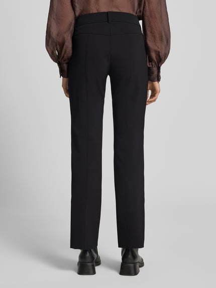 Frauenmodel trägt Slim Fit Schmale Hose mit aufgesetzten Taschen Modell 'FARAH' von CAMBIO in Schwarz, glatte Textur, Ganzkörperansicht Rückansicht. Damen Schmale Hose von CAMBIO.