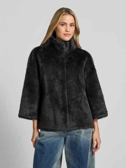 Kobiece model prezentuje Wendejacke aus Kunstfell od Juvia, czarny sztuczne futro, prosty krój, wpuszczane kieszenie, stójka, funkcja dwustronna, długość tyłu w rozmiarze S: 63 cm, szerokość w rozmiarze S: 54 cm, długość rękawów w rozmiarze S: 47 cm, widok całej sylwetki z przodu.