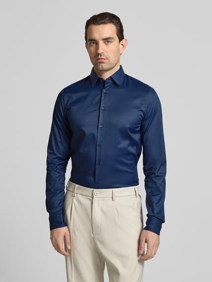 Mannenmodel draagt Slim Fit Business-Hemd met Kentkraag en extra lange mouw van Jake*s in donkerblauw, materiaal-mix met stretch, slanke pasvorm, vooraanzicht van het gehele lichaam.