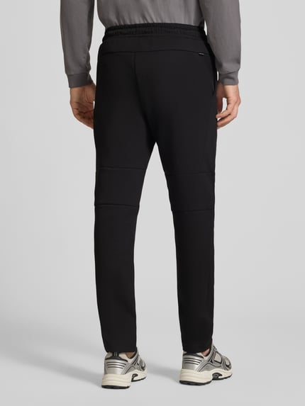 Männermodel trägt schwarze Sweatpants mit elastischem Bund Modell 'GORDON FUSION' von JACK & JONES, Regular Fit, Ganzkörperansicht Rückansicht.