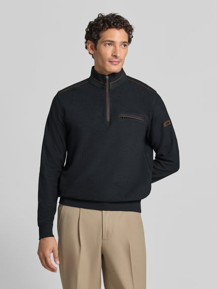 Męski model nosi Sweatshirt mit Stehkragen und Reißverschluss von bugatti, czarny bawełniany krój regular fit, kieszeń na piersi, widok całej sylwetki z przodu.