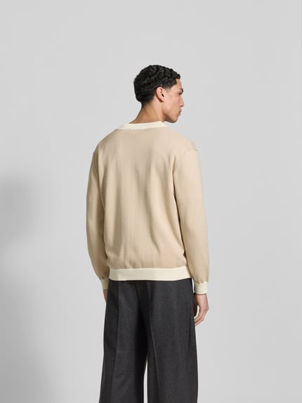 Męski model nosi Cardigan aus reiner Baumwolle od MAISON KITSUNÉ, beżowy, luźny krój, bawełna, widok całej sylwetki z tyłu