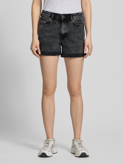 Frauenmodel trägt High Waist Jeansshorts mit Umschlag Modell 'MONI' von Noisy May aus schwarzem Baumwoll-Elasthan-Mix, Regular-Fit, sichtbare Eingrifftaschen, Innenbeinlänge 9 cm, Bundweite 38 cm, Ganzkörperansicht von vorne.