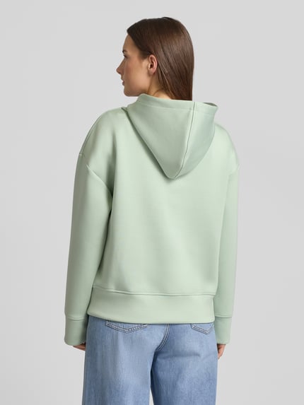 Frauenmodel trägt Regular Fit Hoodie aus Viskose-Mix mit Eingrifftaschen von Fynch-Hatton in Hellgrün, elastische Abschlüsse, Ganzkörperansicht Rückansicht.