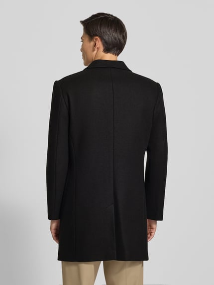 Männermodel trägt Relaxed Fit Mantel aus reiner Baumwolle von MCNEAL in Schwarz, strukturierte Oberfläche, Ganzkörperansicht Rückansicht. Rückenlänge 99 cm, Schulterbreite 46 cm, Brustweite 52 cm, Ärmellänge 66 cm.