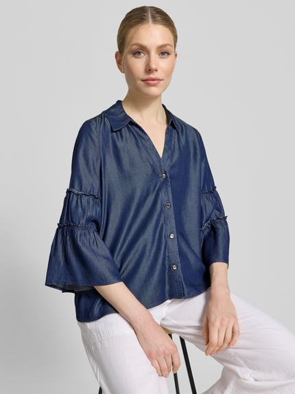Kobiece model prezentuje Regular Fit Jeansbluse aus Lyocell od s.Oliver BLACK LABEL, tkanina stylizowana na denim, kołnierzyk koszulowy, krój regular fit, frędzle, dekolt w serek, listwa guzikowa, długi rękaw, rozszerzane rękawy, materiał lyocell, jasnoniebieska bluzka, prosta faktura, chłodny odcień, całego korpusu z przodu.