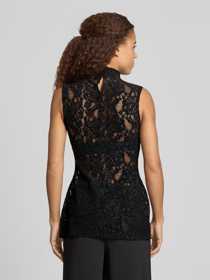 Frauenmodel trägt schwarzes, ärmelloses Top aus Spitze mit Stehkragen, Modell 'COCO' von Topshop, Slim Fit, Rückenlänge 74 cm, Ganzkörperansicht Rückansicht.
