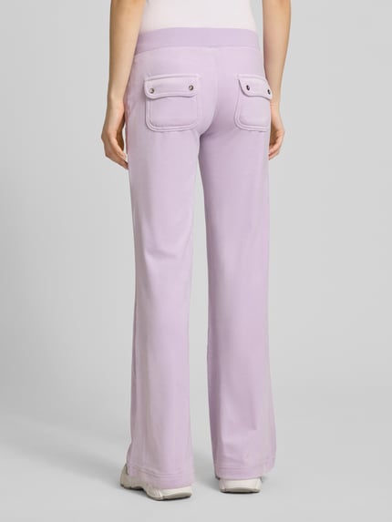 Frauenmodel trägt Low Rise Sweatpants mit Eingrifftaschen Modell 'LAYLA' von Juicy Couture aus Material-Mix mit Stretch-Anteil in Lila, Ganzkörperansicht Rückansicht.