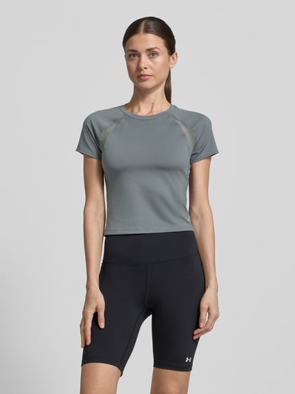 Vrouwenmodel draagt T-shirt met mesh-inzetten en logo van Under Armour, materiaalmix met stretch, kort, ronde hals, ruglengte maat S 45 cm, grijs en zwart, geheel lichaamsaanzicht van voren