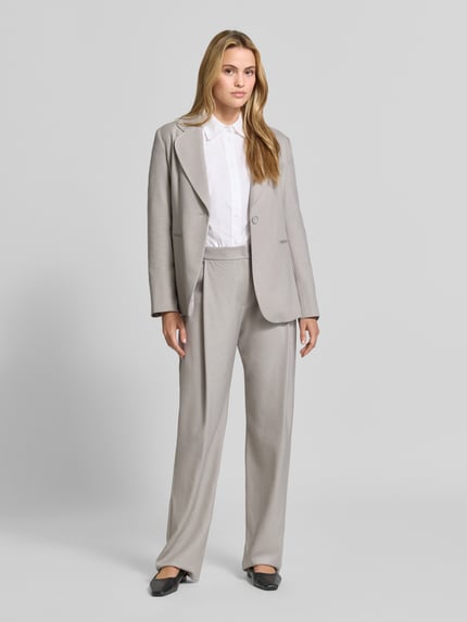 Frauenmodel trägt Straight Fit Hose mit Viskose-Anteil von Emporio Armani in hellem Grau, Bundfalten, Nahaufnahme Ganzkörperansicht von vorne.