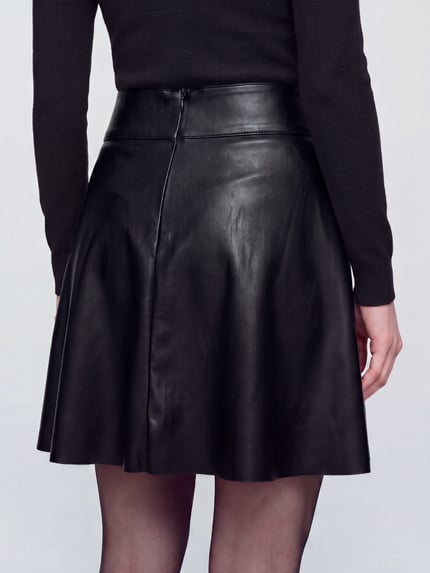Vrouwenmodel draagt Mini-Rock mit Taillenpasse van ONLY in effen mat leerlook met deelnaden, zonder zakken, minilengte, Ganzkörperansicht Rückansicht. Materiaalverwerking: gecoat leer