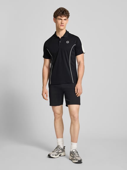 Männermodel trägt Regular Fit Poloshirt mit Logo-Stitching Modell 'EGEO' von SERGIO TACCHINI, Schwarz mit weißen Akzenten, Ganzkörperansicht von vorne.