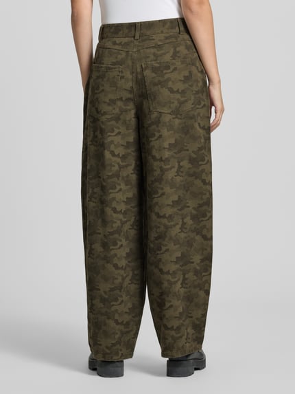 Frauenmodel trägt Jeans mit Camouflage-Muster Modell 'Haven' von Neo Noir, Relaxed Fit, Baumwoll-Viskose-Mix, Ganzkörperansicht Rückansicht.