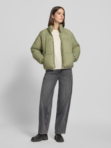 Frauenmodel trägt Pufferjacke mit Stehkragen Modell 'VMBRENDA' von VERO MODA in Hellgrün, unifarben, Cropped-Länge, Webware, Ganzkörperansicht von vorne.