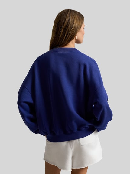 Frauenmodel trägt Regular Fit Sweatshirt aus Baumwoll-Mix von Polo Ralph Lauren in Unifarbe Blau, mit überschnittenen Schultern, Ganzkörperansicht Rückansicht.