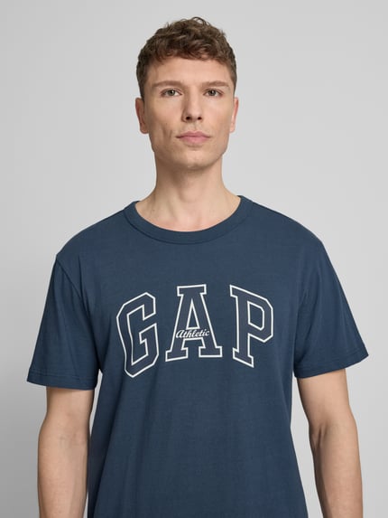 Männermodel trägt T-Shirt mit Logo und Rundhalsausschnitt von GAP in Dunkelblau, Reine Baumwolle, Regular-Fit, Nahaufnahme Oberkörper.