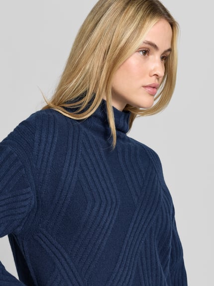 Frauenmodel trägt Pullover aus Kaschmir mit Strukturstrick von Joseph in Dunkelblau, Muster in Strickoptik, Nahaufnahme Oberkörper.