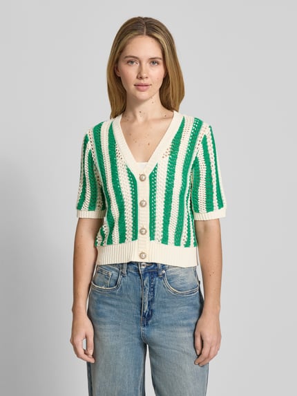 Frauenmodel trägt Cropped Cardigan mit Lochmuster Modell 'Siva' von Lollys Laundry im Strick-Optik aus Baumwoll-Mix, Halbarm, durchgehende Knopfleiste, V-Ausschnitt, elastische Abschlüsse, Rückenlänge 51 cm, Ärmellänge 27 cm, gestreift in Grün und Creme, Ganzkörperansicht von vorne.
