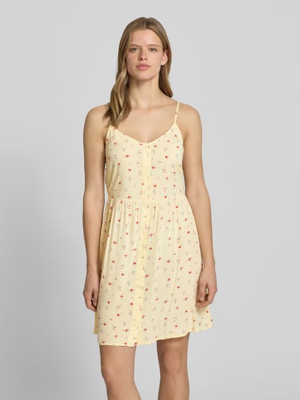 Frauenmodel trägt Leicht ausgestelltes Minikleid aus reiner Viskose Modell 'TALA' von Pieces mit Florales-Allover-Muster in Gelb, V-Ausschnitt, Trägerform:verstellbare Spaghettiträger, Ärmelform:Ohne, Saum:Gerade, Material:Reine Viskose, Ganzkörperansicht von vorne.