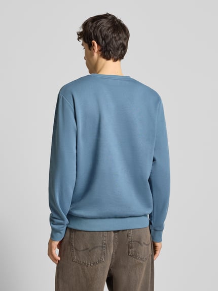 Männermodel trägt Sweatshirt mit Label-Print von Jack & Jones aus Baumwoll-Mix, lockerer Schnitt, gerippte Abschlüsse, Ganzkörperansicht Rückansicht.