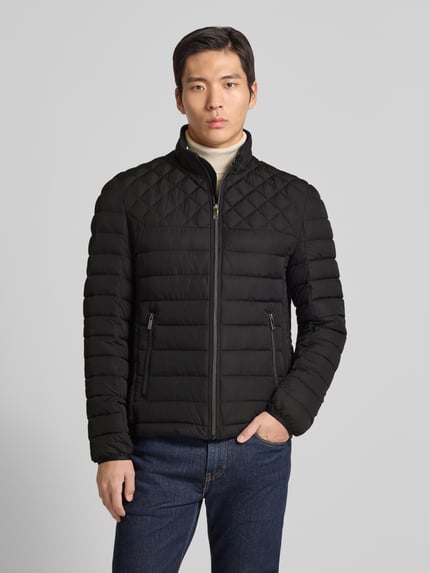 Męski model nosi Slim Fit Steppjacke mit gefüttertem Kragen von Christian Berg Men, czarna kurtka pikowana, kieszenie zapinane na zamek błyskawiczny, elastyczne zakończenia rękawów, krój slim fit, długość tyłu w rozmiarze M: 68 cm, szerokość ramion w rozmiarze M: 47 cm, szerokość w rozmiarze M: 52 cm, długość rękawów w rozmiarze M: 68 cm, widok na cały korpus z przodu