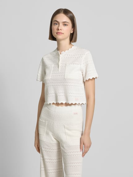 Frauenmodel trägt Damen T-Shirt in Strick-Optik Modell 'Serin' von OH APRIL, Baumwoll-Viskose-Mix, Gerader-Schnitt, Muschelsaum, Label-Patch, Brusttaschen, Farbe Creme, Ganzkörperansicht von vorne.