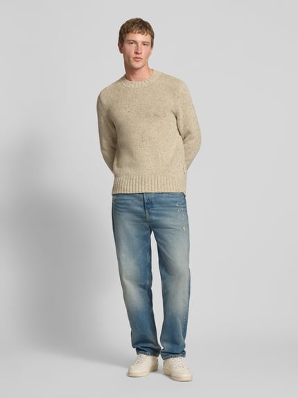 Männermodel trägt Tapered Fit Jeans aus reiner Baumwolle Modell 'SONNY' von Tommy Jeans in denim used-look, regular fit, 5-pocketmodel, labelpatch, studs, riemlussen, knoop en verborgen ritssluiting, puur katoen, ganzkörperansicht von vorne.