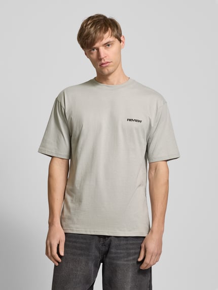 Männermodel trägt Relaxed Fit T-Shirt aus reiner Baumwolle von REVIEW, dezente Logo-Stickerei, Ganzkörperansicht von vorne