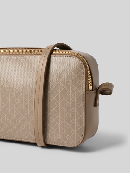 Produktfoto, Camera Bag mit Allover-Logo-Print von CK Calvin Klein in Beige mit goldfarbenem Reißverschluss, glatter Struktur, Hauptfach, schmaler Trageriemen, Logo-Detail, Breite 22 cm, Länge 14 cm, Tiefe 6 cm, Länge Schulterriemen 123 cm.