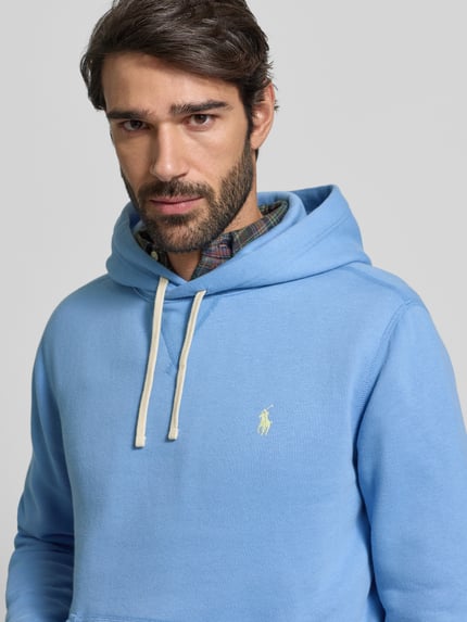 Männermodel trägt Hoodie mit Label-Stitching von Polo Ralph Lauren in Hellblau, Baumwoll-Mix, sichtbarer Tunnelzug und Logo, Nahaufnahme Oberkörper.