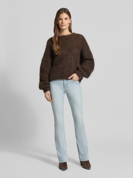 Frauenmodel trägt Flared Fit Jeans im 5-Pocket-Design Modell 'Shakira' von BRAX aus elastischem Baumwoll-Mix, hellblauer Denim, Knopf- und Reißverschluss, Bundweite 36 cm, Innenbeinlänge 82 cm, Ganzkörperansicht von vorne.