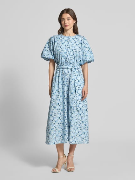 Frauenmodel trägt Midikleid mit Rundhalsausschnitt und Bindegürtel von Rich & Royal in Blau mit Allover-Muster, reine Baumwolle, taillierter Schnitt, verdeckte Knopfleiste, Ganzkörperansicht von vorne.