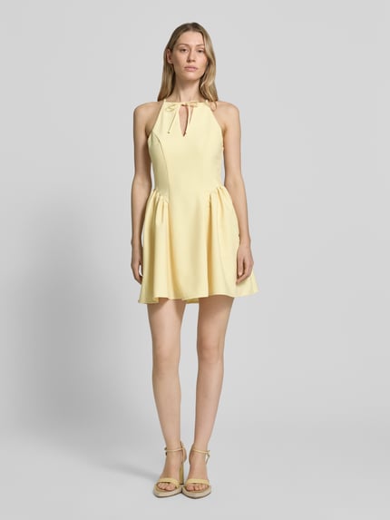 Frauenmodel trägt Cocktailkleid mit Schlüsselloch-Ausschnitt von Little Mistress in zartem Gelb, A-Linie, Rayon-Mix, Minikleid, Ganzkörperansicht von vorne. Rückenlänge 83 cm, Brustweite 40 cm, Schnürung und Rückenreißverschluss.