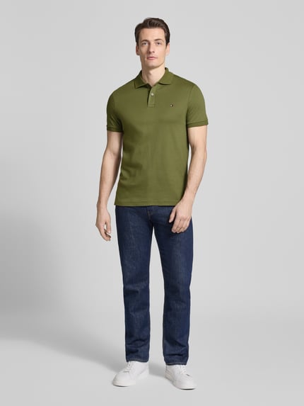 Männermodel trägt Regular Fit Koszulka polo aus reiner bawełna Modell 'LIQUID COTTON' von Tommy Hilfiger, melanż, wyhaftowane logo, kołnierzyk polo, krótki rękaw, prążkowane zakończenie rękawów, wykończenie z rozcięciami po bokach, całkowity widok z przodu