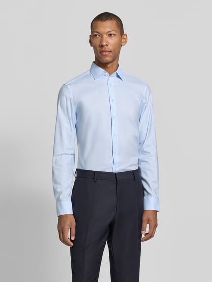 Männermodel trägt Slim Fit Businesshemd aus reiner Baumwolle von JAKE*S, hellblau, feines Webmuster, Knopfleiste, Nahaufnahme Oberkörper.