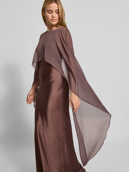 Kobiece modelka nosi długa sukienka z satyny Maxikleid aus Satin von SWING, elastyczna mieszanka materiałów, dopasowany krój, półprzezroczysta etola, cienkie ramiączka, dekolt w serek, długość tyłu w rozmiarze 36: 133 cm, szerokość w rozmiarze 36: 31 cm, widok całej sylwetki z przodu.