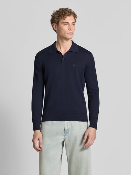 Männermodel trägt dunkelblaues Slim Fit Poloshirt aus reiner Baumwolle von ARMEDANGELS, glatte Struktur, Ganzkörperansicht von vorne.