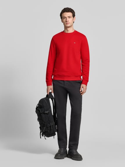 Männermodel trägt rood Sweatshirt met label-stitching, regular fit van Napapijri, katoen, model 'BALIS', lange mouwen, ronde hals, Ganzkörperansicht von vorne.