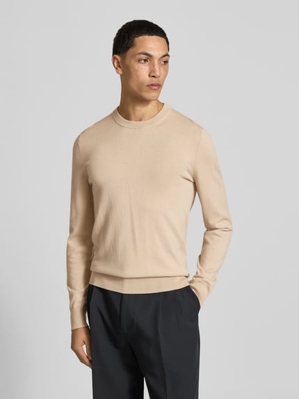 Männermodel trägt Wollpullover mit gerippten Abschlüssen von Filippa K in Beige, gerade geschnitten, Rundhalsausschnitt, Nahaufnahme Oberkörper.
