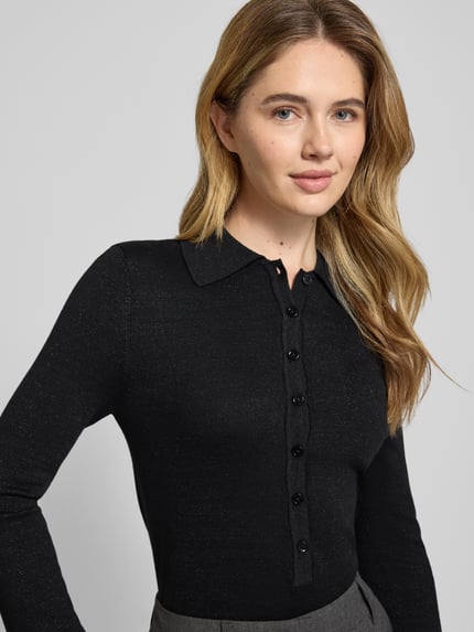 Vrouwenmodel draagt slim fit langarmshirt uit lyocell-katoenmix Flura Lurex van Selected Femme, effen zwart, schimmereffect, Nahaufnahme bovenlichaam.