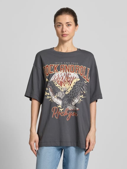 Vrouwenmodel draagt Oversized T-shirt uit puur katoen model 'LILIE' van Vero Moda, look: effen, oversized fit, motiefprint, korte mouw, puur katoen. Ganzkörperansicht van voren.