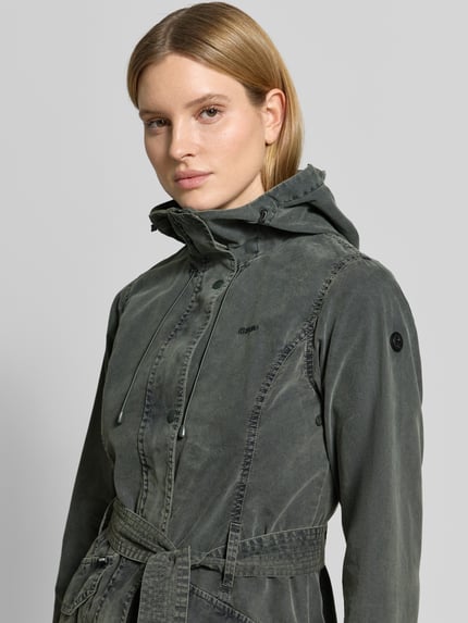 Kobiece model nosi kurtkę Jacke mit Bindegürtel Modell 'PREA' od khujo z mieszanki bawełny, krój regular fit, kaptur, wyhaftowane logo, wiązany pasek, szaro-oliwkowy kolor, tekstura spranego materiału, szerokość ramion w rozmiarze S: 44 cm, szerokość klatki piersiowej w rozmiarze S: 45 cm, długość tyłu w rozmiarze S: 37 cm, długość rękawów w rozmiarze S: 53 cm, zbliżenie na górną część ciała z przodu.