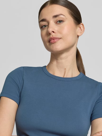 Vrouwenmodel draagt T-shirt met fijnrib en ronde hals van Jake*s Casual, katoenmix met stretch, slim fit, golvende zoom, ruglengte maat S 51 cm, kleur blauw, gladde textuur, nahaufnahme bovenlichaam.