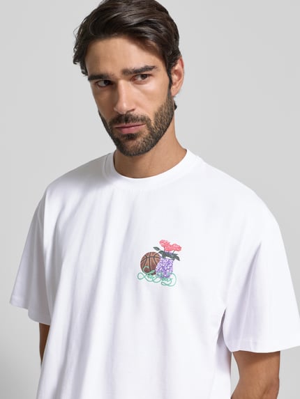 Männermodel draagt T-shirt met labelprint en ronde hals van Les Deux, puur katoen, relaxed fit, model 'Cole Table', ruglengte maat M 71 cm, Nahaufnahme Oberkörper.