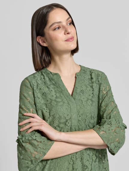 Frauenmodel trägt Loose Fit Spitzenkleid aus Baumwoll-Mix Modell 'HONEY' von Vero Moda, unifarben, Spitzen-Muster, 3/4-Arm, V-Ausschnitt, Nahaufnahme Oberkörper.