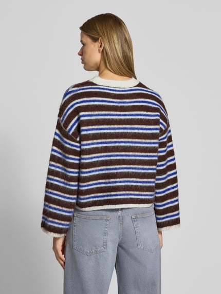 Frauenmodel trägt Pullover aus Schurwolle mit Rundhalsausschnitt von PIECES, mehrfarbig gestreift, Strickoptik, Ganzkörperansicht Rückansicht.