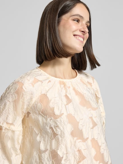 Frauenmodel trägt Relaxed Fit Bluse mit 3/4-Arm und Perlen von Milano Italy, semitransparenter Allover-Look in Creme, Nahaufnahme Oberkörper.