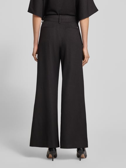 Vrouwenmodel draagt Hose mit weitem Bein und Eingrifftaschen Modell 'Evie Bellevue' van MOS MOSH, zwart, rechte lijnen, gladde textuur, Ganzkörperansicht Rückansicht. Materialmix met viscose, wijd model, steekzakken, maat 36.